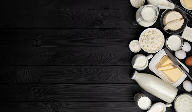 Dairy products on black wooden background, top view