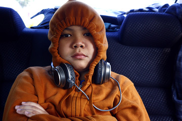 Young Filipino boy wearing sweater with hood and headphones around his neck