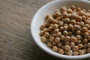 Soybeans in a white plate on wooden background. 