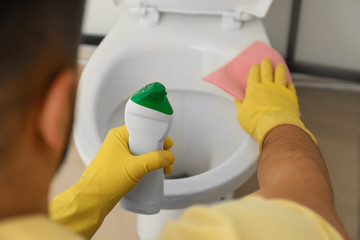 Man cleaning toilet bowl in bathroom, closeup