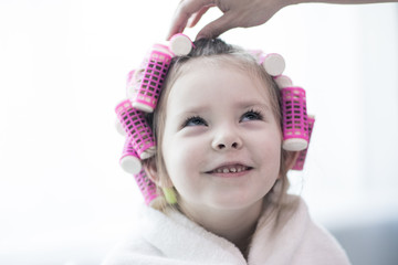 portrait of emotional little pretty girl with hair curlers
