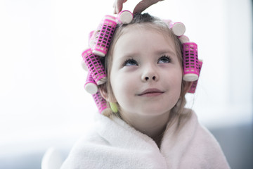 portrait of emotional little pretty girl with hair curlers