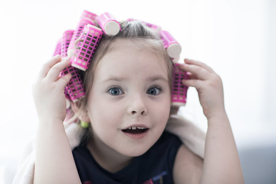 portrait of emotional little pretty girl with hair curlers