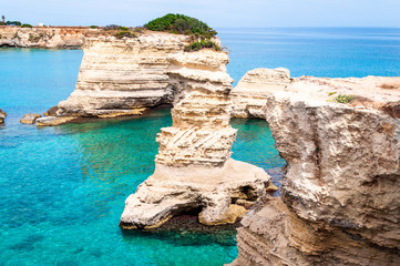 Fototapeta premium Torre Sant Andrea beach with its soft calcareous rocks and cliffs, sea stacks, small coves and the jagged coast landscape. Crystal clear water shape white stone create natural stacks. Melendugno Italy