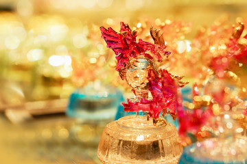 Closeup glass blower in red dragons clutching on ball shape and music box with blurry background....