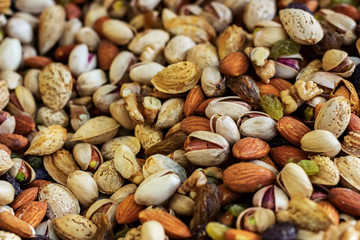 Mix of different delicious nuts and raisins background. Close up. Soft focus.