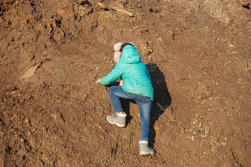A girl is climbing a mountain. The child is dirty clothes.