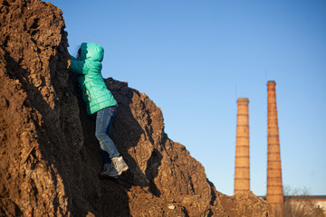 A girl is climbing a mountain. The child is dirty clothes.