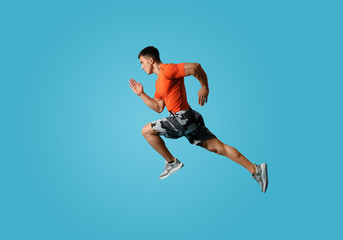 Fototapeta na wymiar Athletic young man running on light blue background, side view
