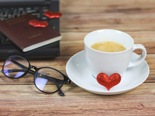 glasses beside on wooden table with computer notebook and passport with two red hearts on it. Long distance relationship concept.
