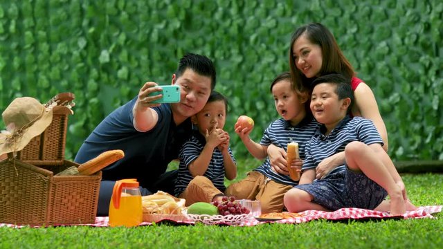 Asian family taking a selfie photo together at park