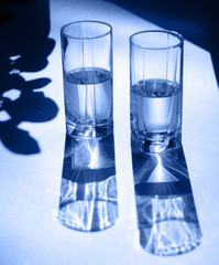 Two glasses of water. Bright light and contrasting shadows.