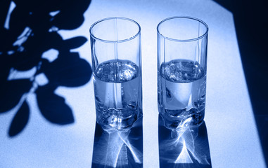 Two glasses of water. Bright light and contrasting shadows.