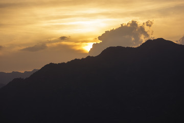 A view of a sunset behind a high mountain surrounding the village of Sarahan in Himachal Pradesh in the Indian Himalayas.