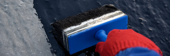 Worker applies bitumen mastic on the foundation
