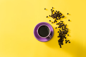 Purple cup of coffee with coffee beans on yellow background