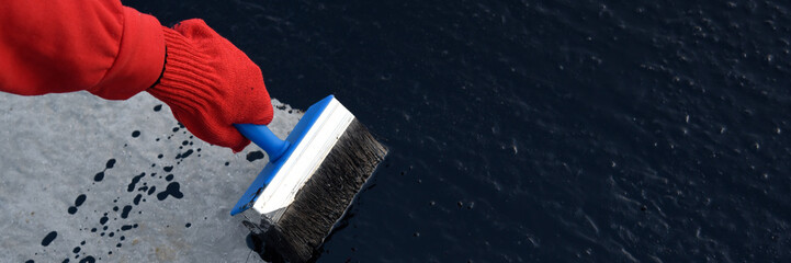 Worker applies bitumen mastic on the foundation