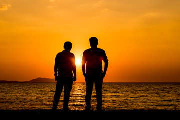 Silhouette people show hands feel relax stand on the beach at sunset time with sunlight sky background.