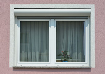 Fototapeta na wymiar Fenster mit Rollladen in einer gemauerten, verputzten und gestrichenen Fassade eines modernen Wohnhauses