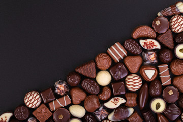 various chocolate candy on black table background, dessert sweets.