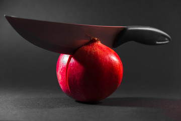 pomegranate and knife on black background
