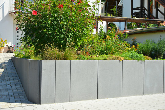 Ungestrichene senkrecht eingebaute Betonelemente als Mauer und Strukturelement vor  einem Wohnhaus