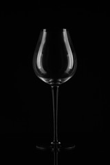 Empty wine stem glass on a thin long leg on a black background located symmetrically. Close up. Text space.