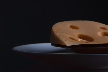 Milk product concept. Slice of curd cheese laying on two plates looking like half moon at night. Close up. Text space. Studio shot