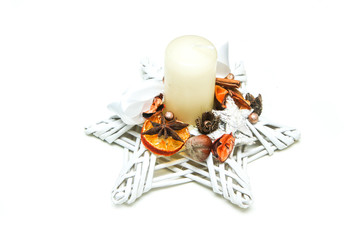 The traditional wicker candlestick in star shape with some decorative pieces of cinnamon and star anyse and slice of dried orange. 