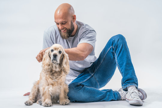 Attractive Bearded Man Posing In Studio Photo With An American Cocker Dog On White Background