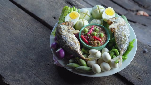 Set plate of fried mackerel with shrimp paste sauce and vegetables. Thai dish. pan shot. 4K