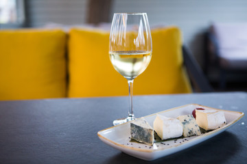 glass of white wine and a plate with cheeses