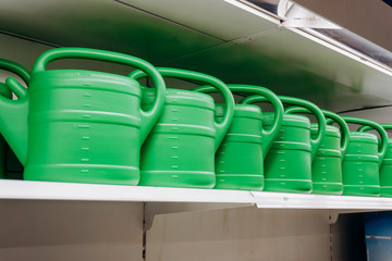 A lot of green watering cans for watering in the shop window. Gardening. Tools for garden and vegetable garden.