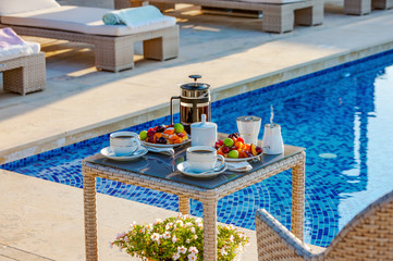 Serving table with fruits and coffee near the outdoor pool.