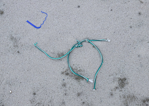 The Cut-off End Of An Old Plastic Rope, Lying On The Beach As Waste, Brought By The Sea