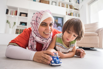 Mother and cute son playing with car toy at living room