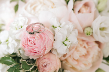 Wedding engagement rings and flowers wedding bouquet background, selective focus, macro