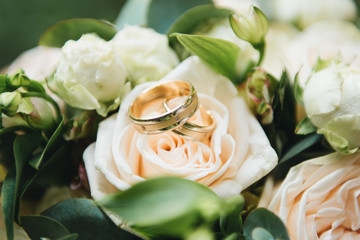 Wedding engagement rings and flowers wedding bouquet background, selective focus, macro
