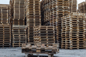 Big stack of wooden pallets outside.