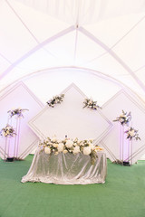 Decor concept for wedding and holiday, beautiful white tent decorated with flowers for the holiday, Presidium with diamonds of the bride and groom