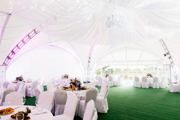The concept of decoration for wedding and celebration, a beautiful white tent decorated with flowers for the holiday