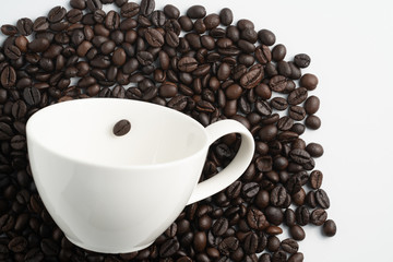 white cup on black coffee bean pile top view wite white background