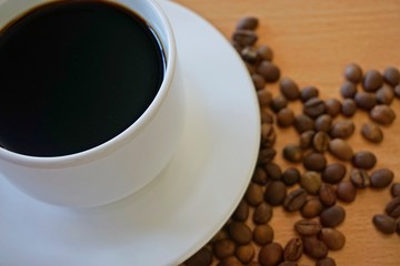 cup of coffee with beans on wooden table