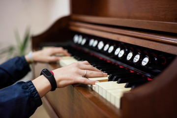 The hands of a young girl on the keys of an ancient piano play a familiar melody