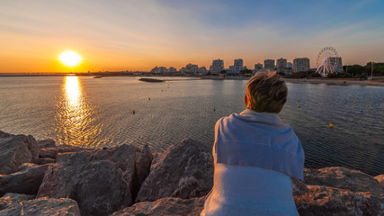 Femme regardant un coucher de soleil sur La Grande Motte, Hérault, France.	