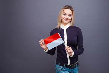 Immigration and the study of foreign languages, concept. A young smiling woman with a Monaco flag...