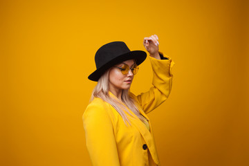 Cheerful trending young woman in bright clothes on yellow background, copy space. Cool blonde