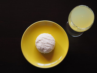 Homemade cottage cheese in a yellow plate and milk whey drink in a wine glass on a black background, top view.  Healthy and diet food for good health closeup.