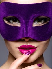 Portrait of a beautiful  woman with purple nails and violet theatre mask on face.