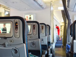 Cabin airliner, blue leather seats with multimedia system, passage between the seats. blurred...